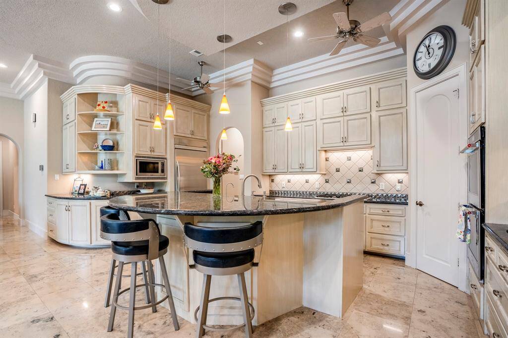 The spacious kitchen is central to this luxurious single level home with sweeping views to the backyard oasis.