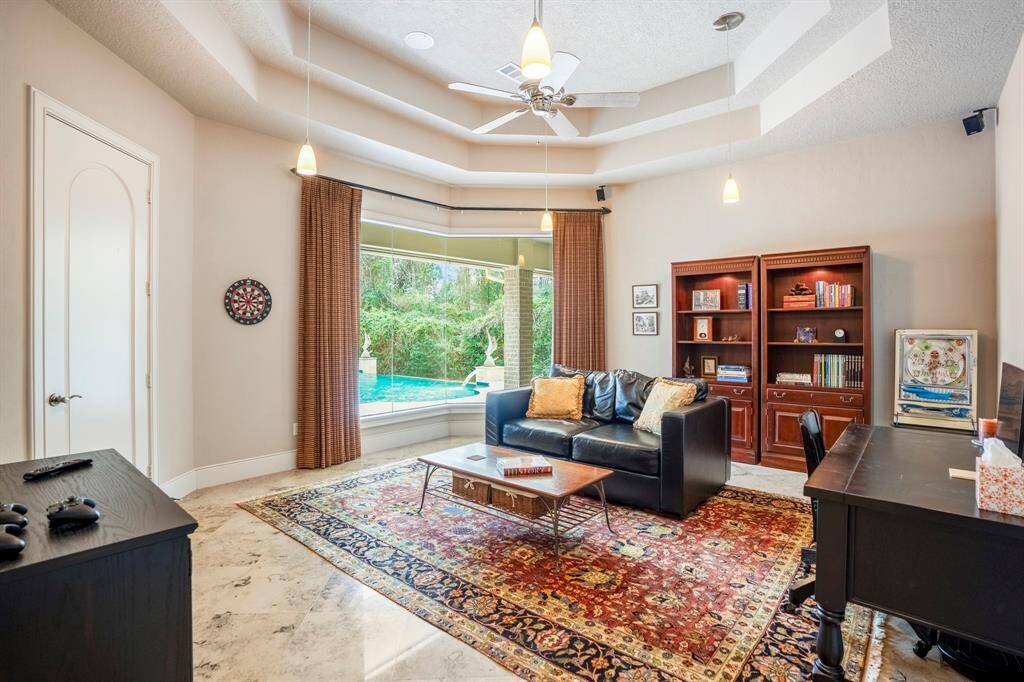 The spacious game room has an amazing view of the pool and backyard with features including tray ceilings, fun pendant lighting, wired for speakers, and a closet for optimal organization.