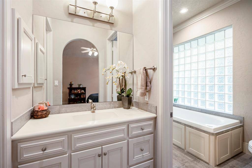The Hollywood bath, accessible from both bedroom two and three, features a neutral color palette and is bathed in natural light from the glass block wall. Each of the secondary bedrooms also includes spacious walk-in closets.