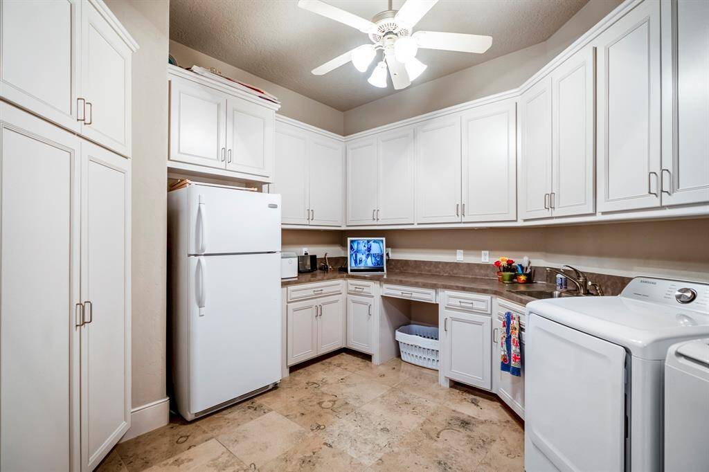 The laundry room has so much efficiently designed storage, a sink, hanging rod, room for a second refrigerator and even space to do craft projects!