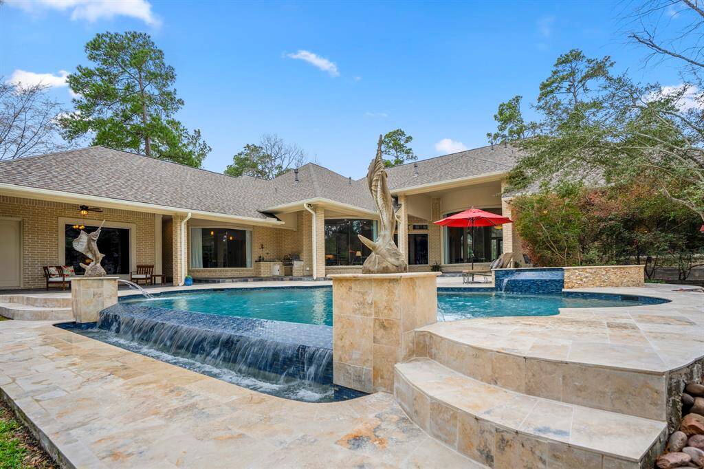 This fabulous one-story estate home features expansive windows that frame picturesque views of the outdoor oasis. The infinity edge pool, spa with waterfall, and bubblers create a serene atmosphere, while the summer kitchen and the impressive covered area (over 1,000 square feet spanning almost the entire length of the home) provide ample space for outdoor living and entertaining.