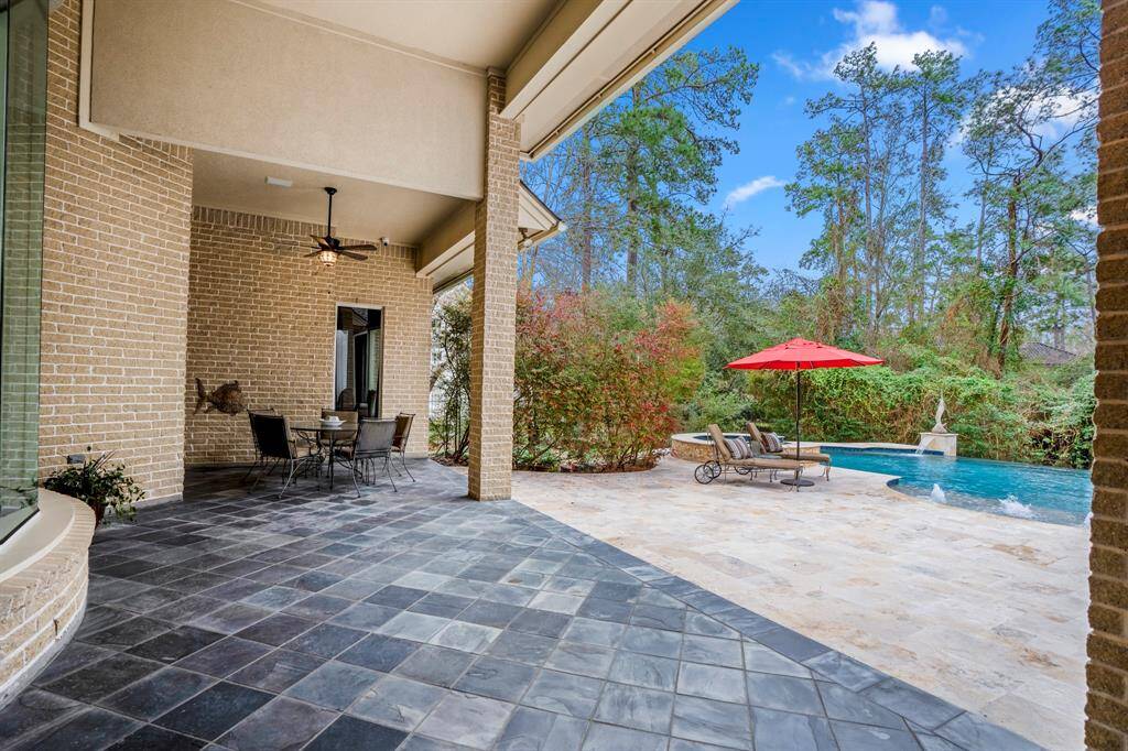 The expansive covered lanai features natural slate tiles set on the diagonal and ceiling fans, creating a stylish and comfortable outdoor living space.