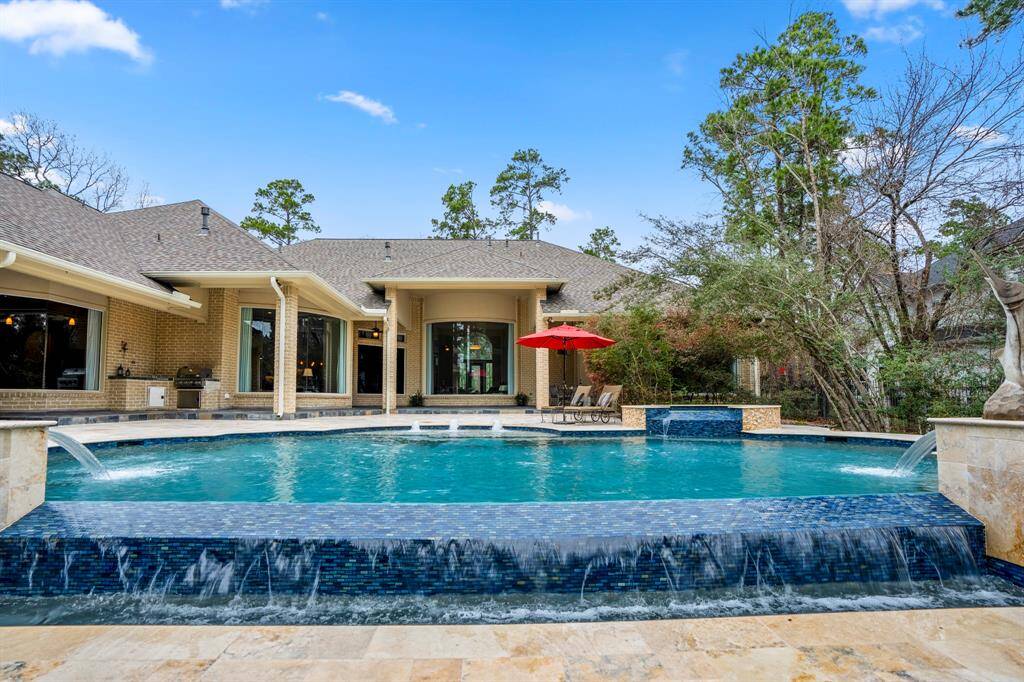The exquisite pool (recently updated tile, pool surface and natural stone decking) is the centerpiece of this private backyard with travertine tile surrounding the pool set against the turquoise blue water and infinity edge waterfall.