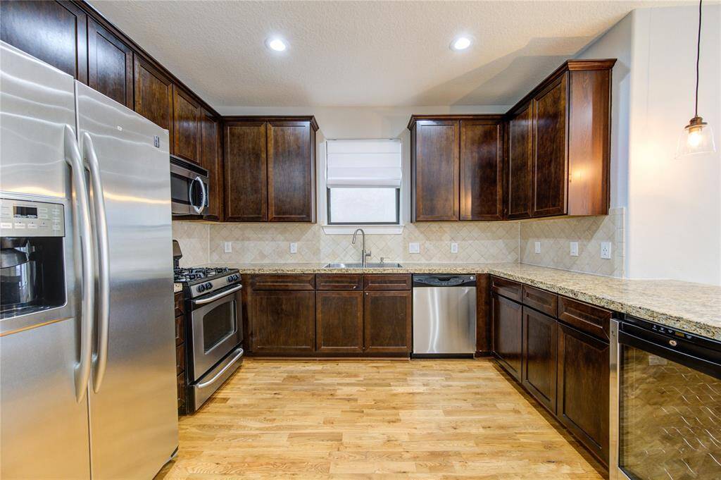 A chef’s dream, this gourmet kitchen boasts sleek granite countertops that provide ample space for meal prep and entertaining. The custom cabinetry offers abundant storage, complemented by modern stainless steel appliances, including a gas range, built-in microwave, and dishwasher for effortless cooking.