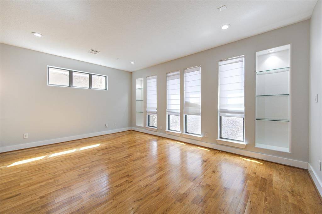 Flooded with natural light from oversized windows, the spacious living area features rich wood flooring and an open layout, making it perfect for both relaxing and entertaining.