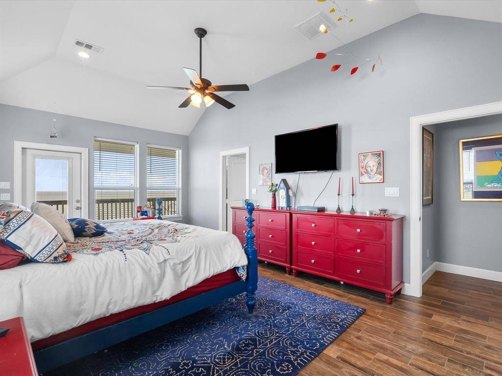 Spacious bedroom with high ceiling, large windows for natural light  and a door leading to a balcony.