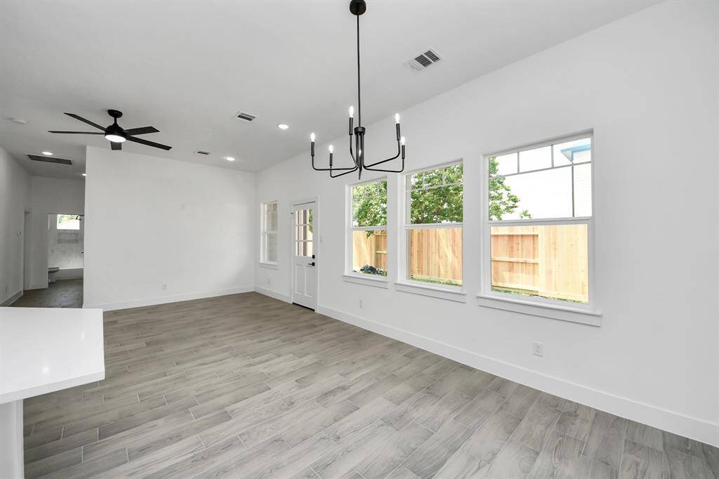 Natural light floods the dining area through a trio of tall windows—just steps from the kitchen and back patio for perfect indoor-outdoor flow.