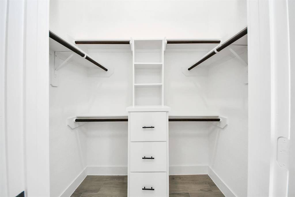 One of two walk-in closets in the primary suite—built-in shelving, hanging rods and drawers  keep your wardrobe perfectly organized.