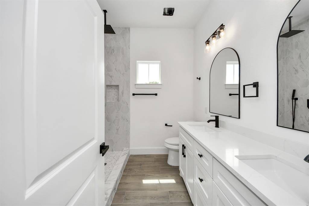 The primary bath offers dual sinks with modern black hardware, quartz countertops, and bold black accents.