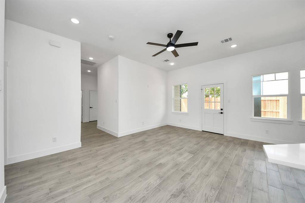 Bright and airy living space with recessed lights, modern fan, and large windows letting the sunshine in!