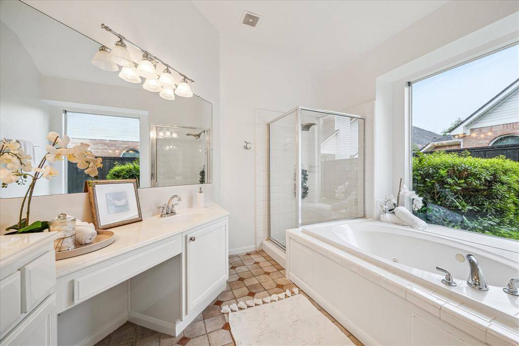 Primary bathroom features double sinks, vanity, jetted tub and walk-in shower.