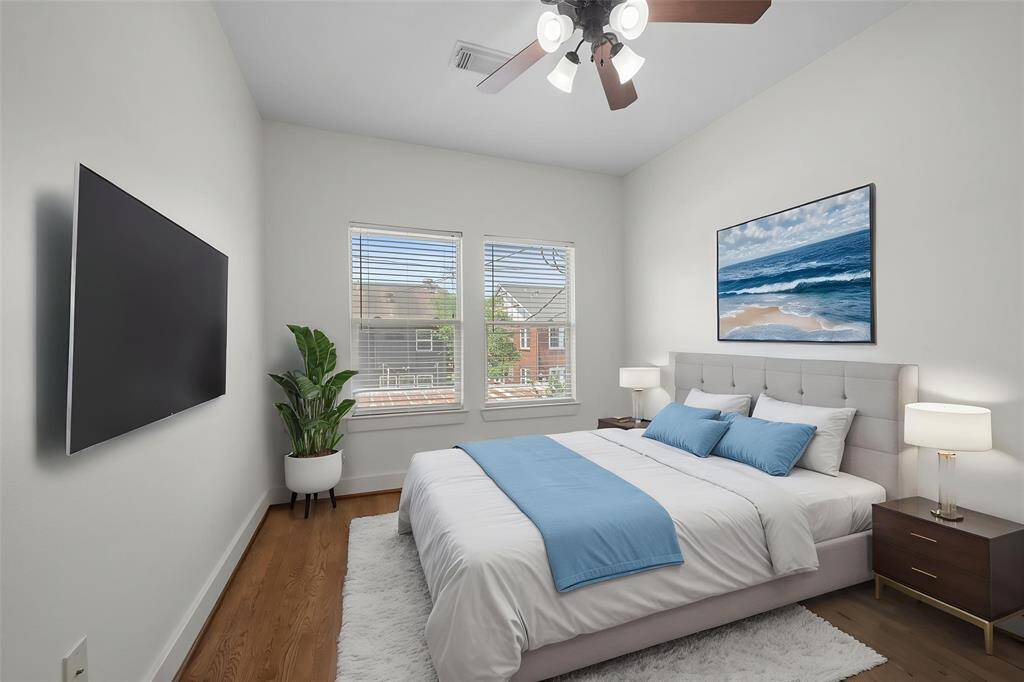 Virtually Staged: Lovely secondary bedroom featuring hardwood floors, dark-stained ceiling fan, and large windows with privacy blinds.