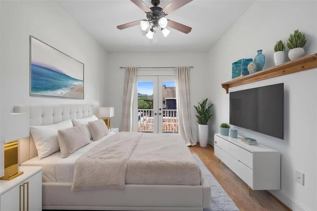 Virtually Staged: Lovely secondary bedroom featuring hardwood floors, dark-stained ceiling fan, and large glass doors with access to the balcony.