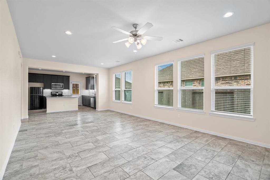 Modern kitchen with granite countertops, stainless steel appliances, dark cabinetry, and tile flooring. Features an island with seating, ample natural light, and a neutral color palette.
