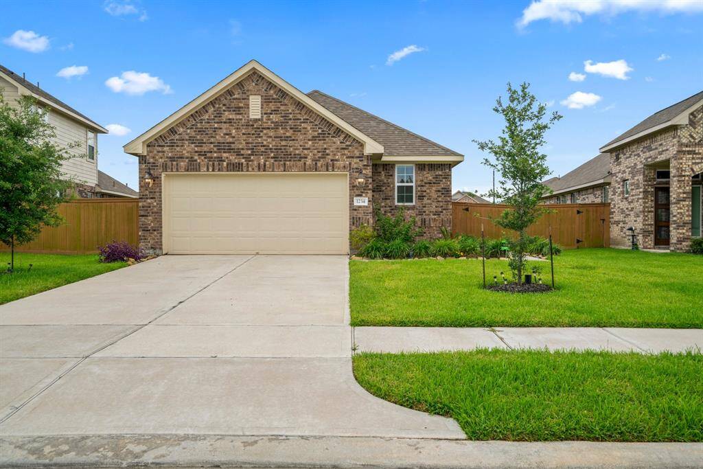 Bright and spacious open-concept living area with large windows, tile flooring, and a modern kitchen featuring dark cabinetry and stainless steel appliances.