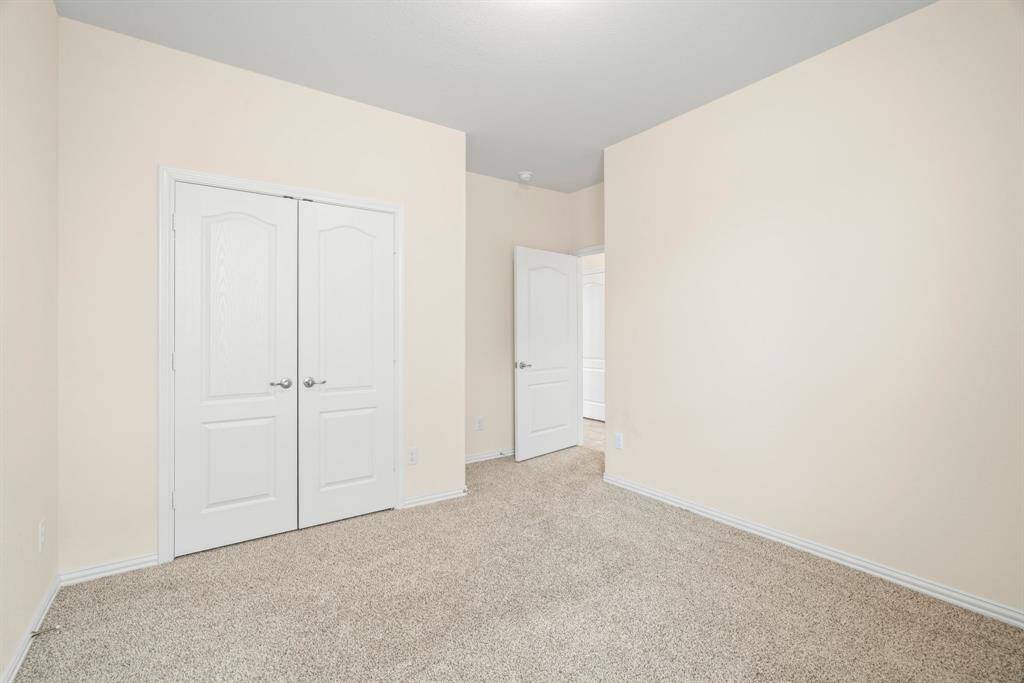 Bathroom features a spacious double vanity with sleek countertops, a large mirror, and a modern glass-enclosed shower. The neutral tile flooring and soft lighting create a clean, inviting atmosphere.