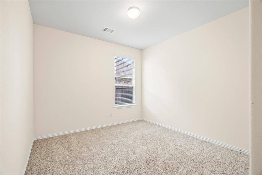 Bright room with neutral walls and carpeted floors. It includes a double-door closet and a single door leading to another area, ideal for a bedroom or office space.
