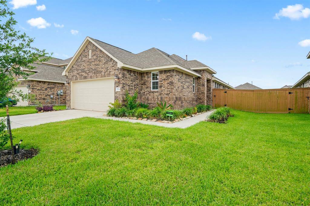 Charming single-story brick home with a neatly manicured lawn and a two-car garage. The driveway is spacious, and the property features a newly planted tree in the front yard, offering great curb appeal in a suburban setting.