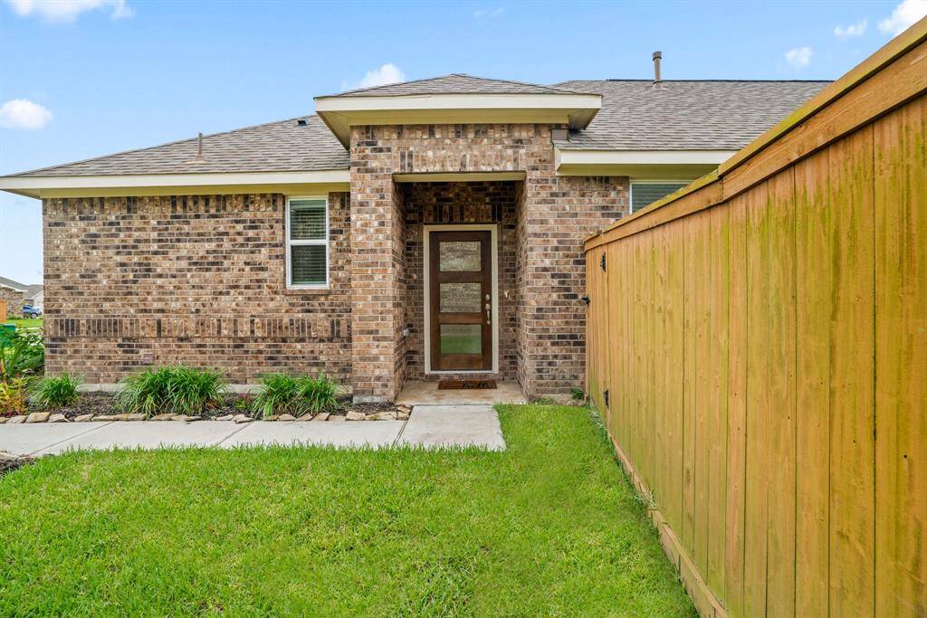 This is a charming single-story brick home with a two-car garage. It features a well-maintained lawn and landscaped front yard, nestled in a quiet neighborhood. A wooden fence provides backyard privacy.