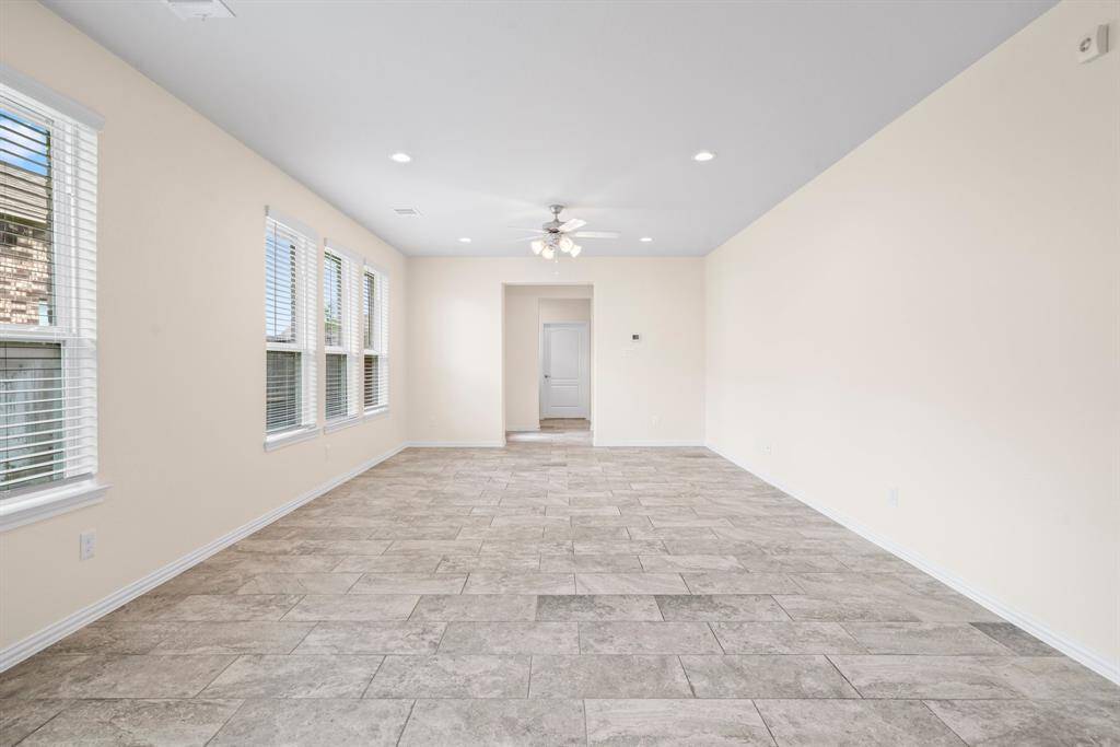 This modern kitchen features sleek dark cabinets, stainless steel appliances, and a spacious granite island. It boasts ample natural light from large windows and has a clean, contemporary design with a tile floor and subway tile backsplash. Perfect for cooking and entertaining.