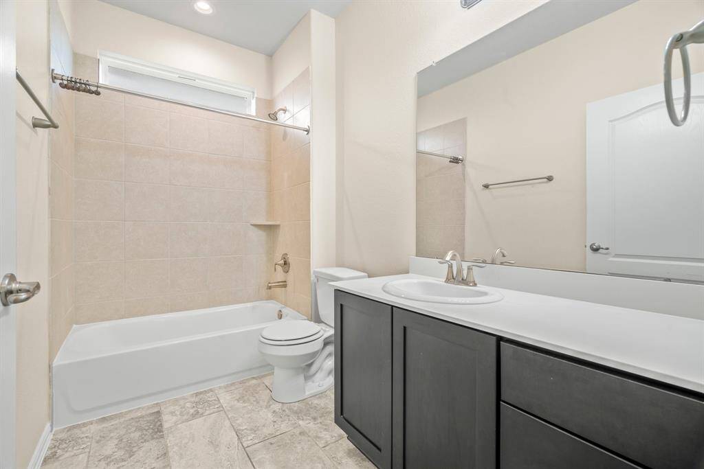 This modern kitchen features dark cabinetry, granite countertops, and stainless steel appliances. The space includes a central island and a door leading outside, creating a bright and functional cooking and dining area.