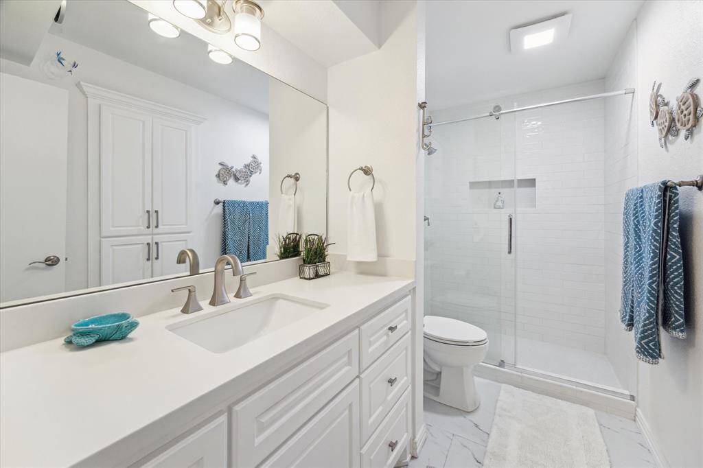 Bathroom with quartz countertop and walk in shower.