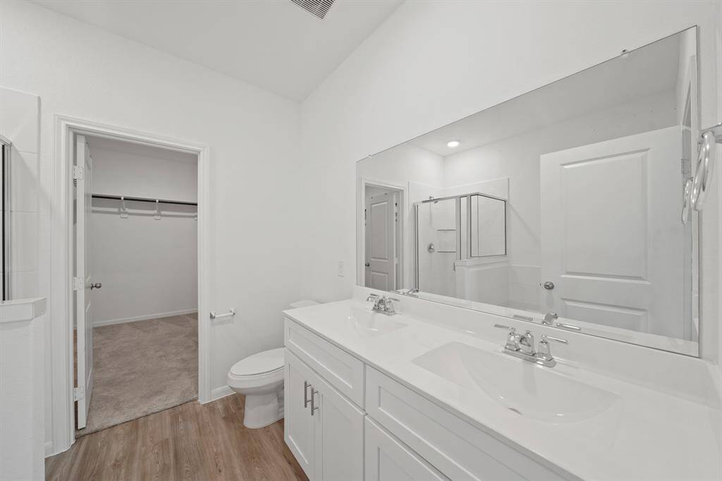 This bright and inviting primary bath offers double vanities and ample space for a relaxing start or end to your day.