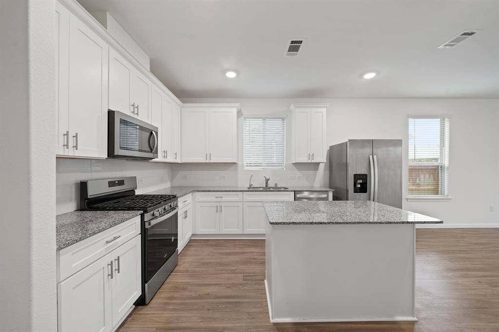 This beautifully designed kitchen features stunning marble countertops, stainless steel appliances, and classic white cabinets for a fresh, clean look.
