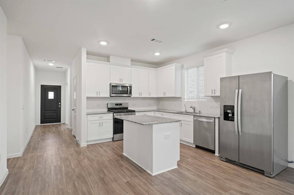 The sprawling island with breakfast bar seating serves as a versatile centerpiece, providing additional workspace, storage, and seating for casual dining or entertaining.