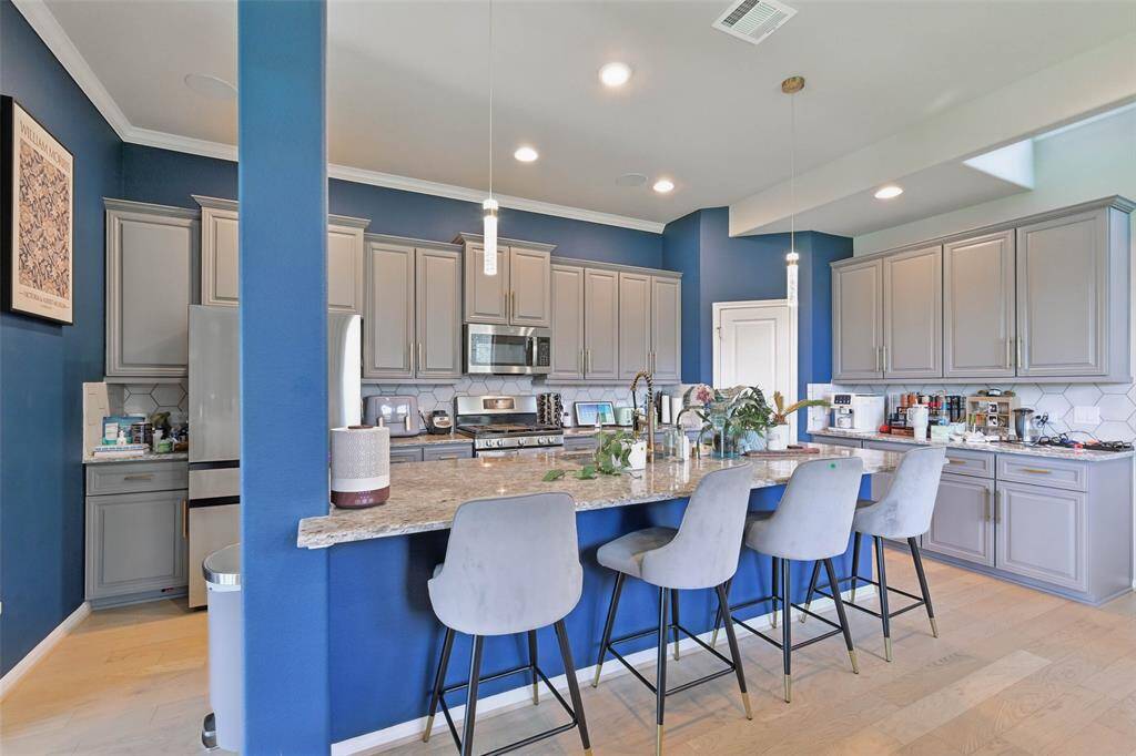 Chef's eat-in island kitchen features lengthy granite countertops, 42" cabinets with crown molding and stainless steel appliances