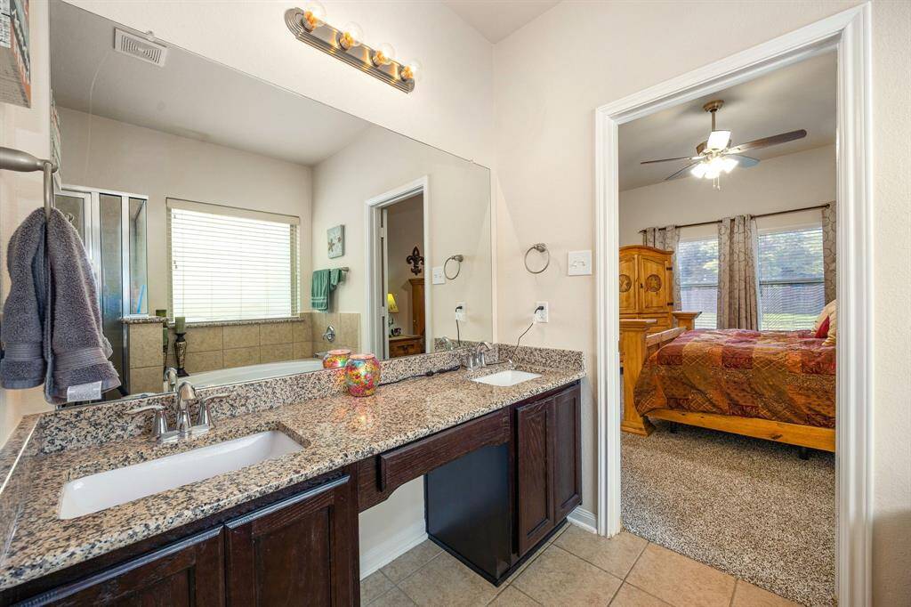 Primary ensuite bathroom with granite countertops, dual sinks and makeup vanity