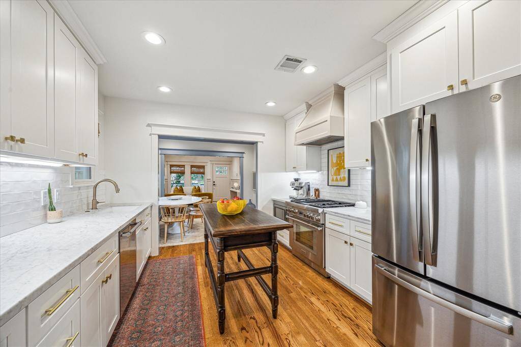 The kitchen is thoughtfully placed and featured as the heart of the home. Stunning hardware and stainless appliances are the chef's kiss!