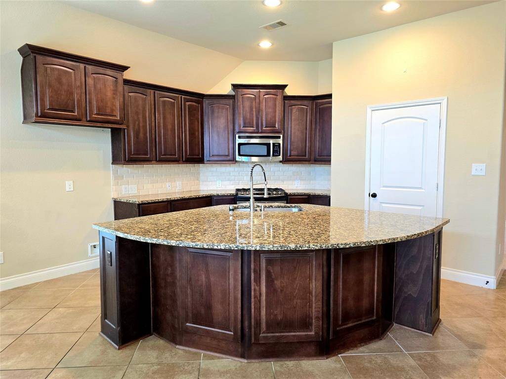 Island Kitchen with space for Chairs. Stainless Steel Microwave, Stove Range and Dishwasher. Easy access to shelved pantry and plenty of cabinet space.