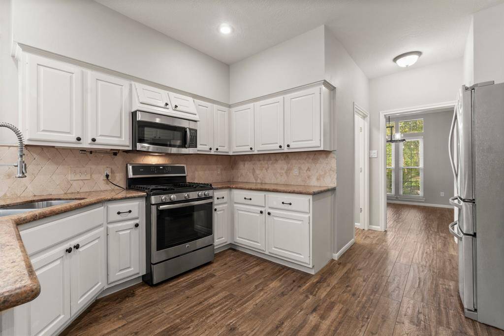 This kitchen features modern stainless steel appliances. It opens to a bright dining area with large windows, creating an inviting space for cooking and entertaining.