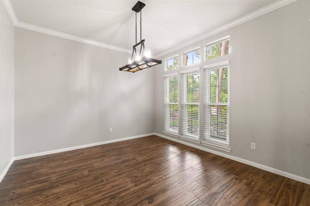 Bright dining room with large windows, wood flooring, and modern light fixture. Ideal for natural light and cozy meals.