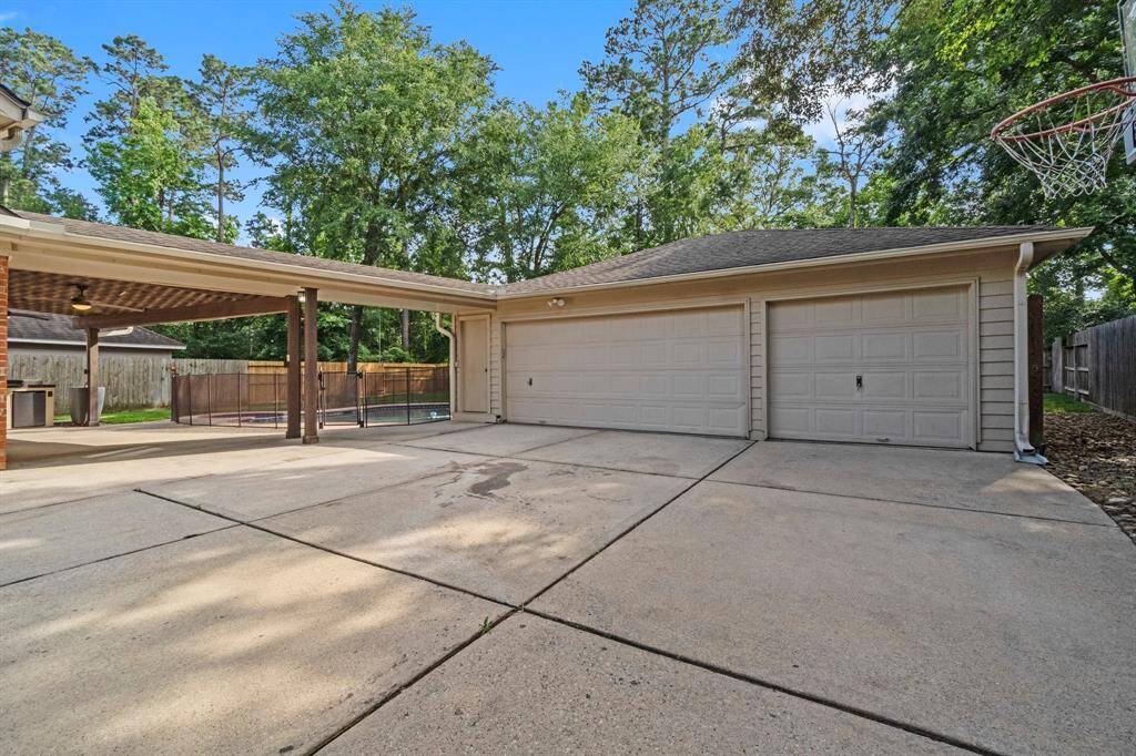 Spacious driveway with a three-car garage and a covered patio. The area is surrounded by trees, providing a private and serene atmosphere. Ideal for anyone seeking ample parking and outdoor space.