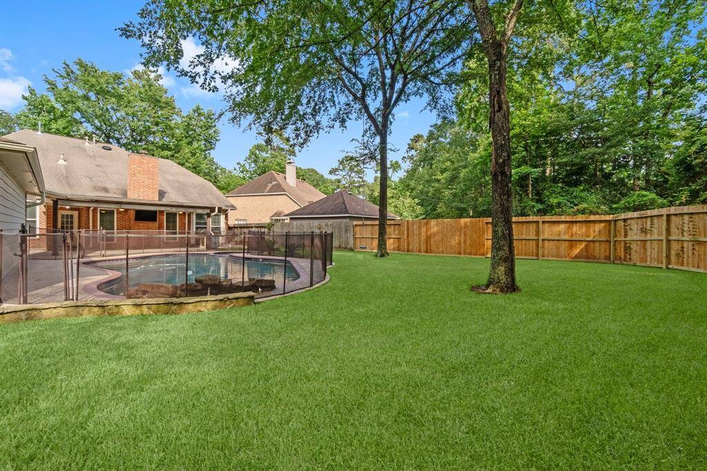 This fully fenced in backyard features a spacious, lush lawn and trees. A fenced-in pool area offers safety and relaxation, bordered by trees for added privacy. Ideal for outdoor activities and enjoyment.