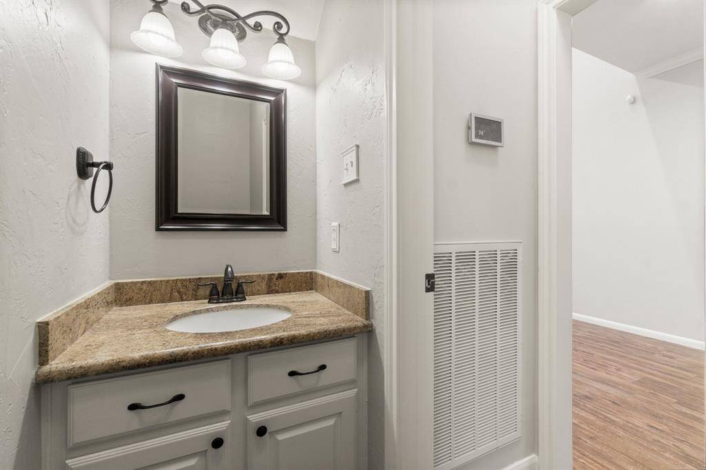 This cozy powder room comes furnished with a granite countertop, undermount sink, and elegant lighting above a framed mirror. Your guests will appreciate the elegant touches.