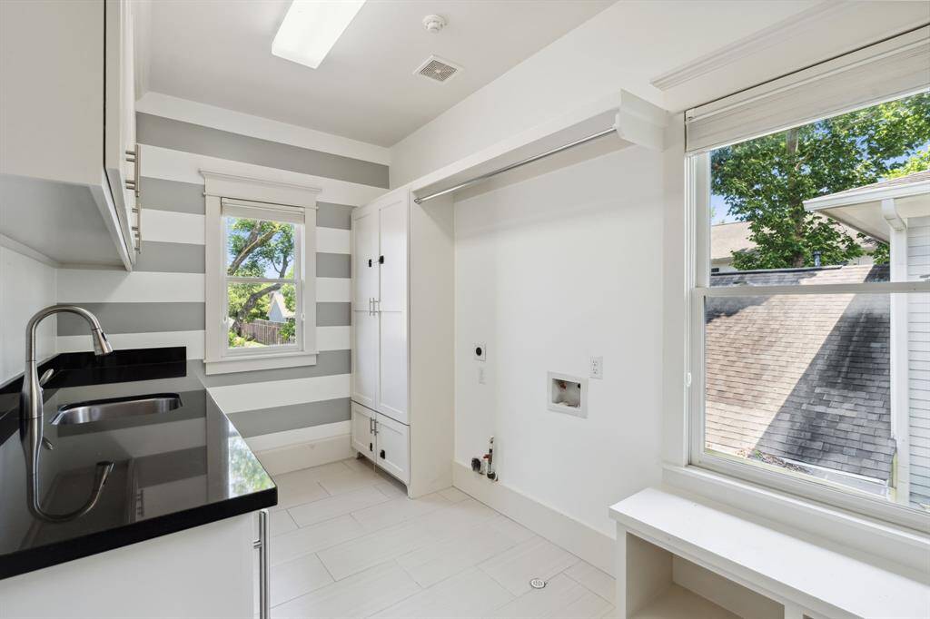 Large laundry room with beverage fridge, utility sink, and storage galore.