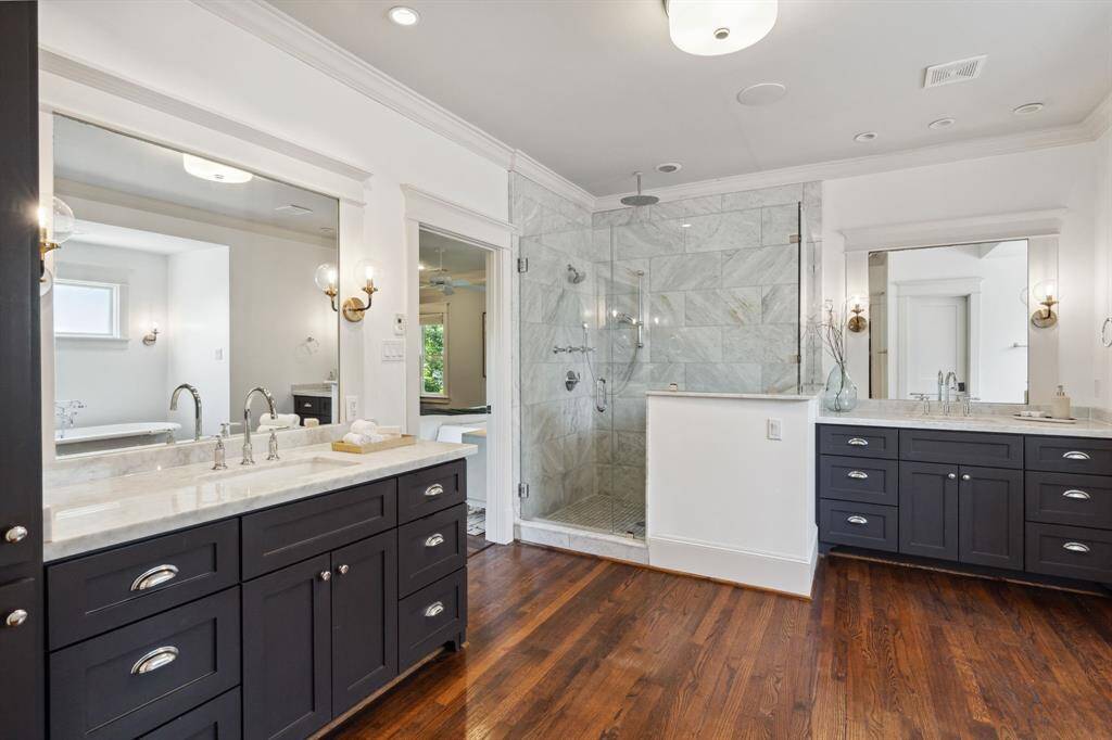 Thoughtfully designed with dual vanities, marble like-tiled walk-in shower, and brass fixtures.