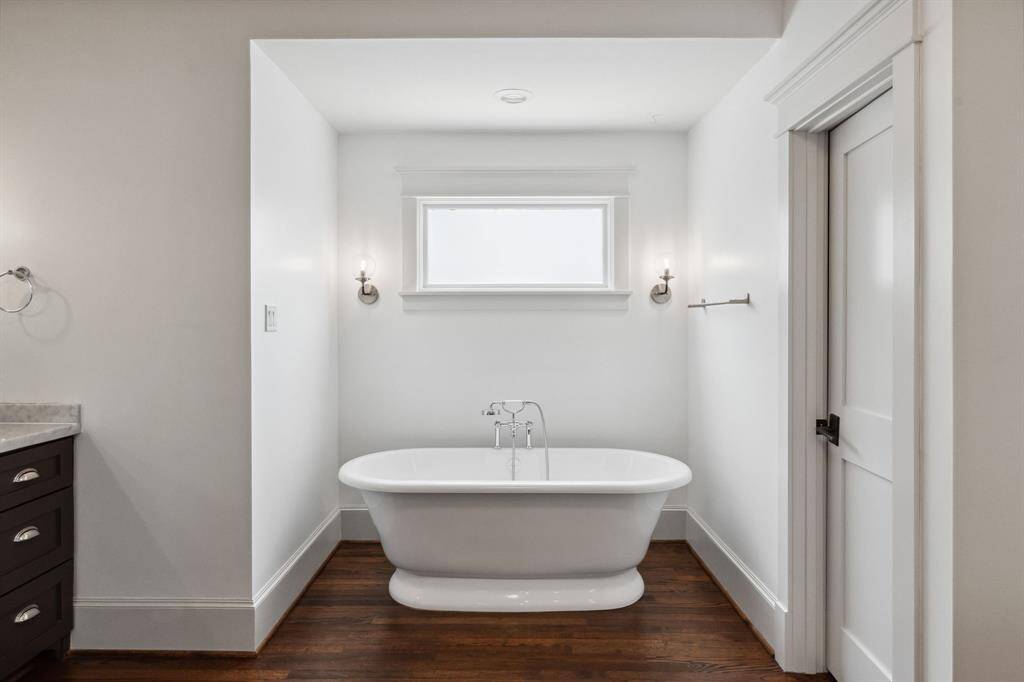 A soaking tub framed by sconces and natural light.