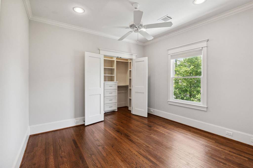 Secondary bedroom with hardwood floors, custom closet, and natural light