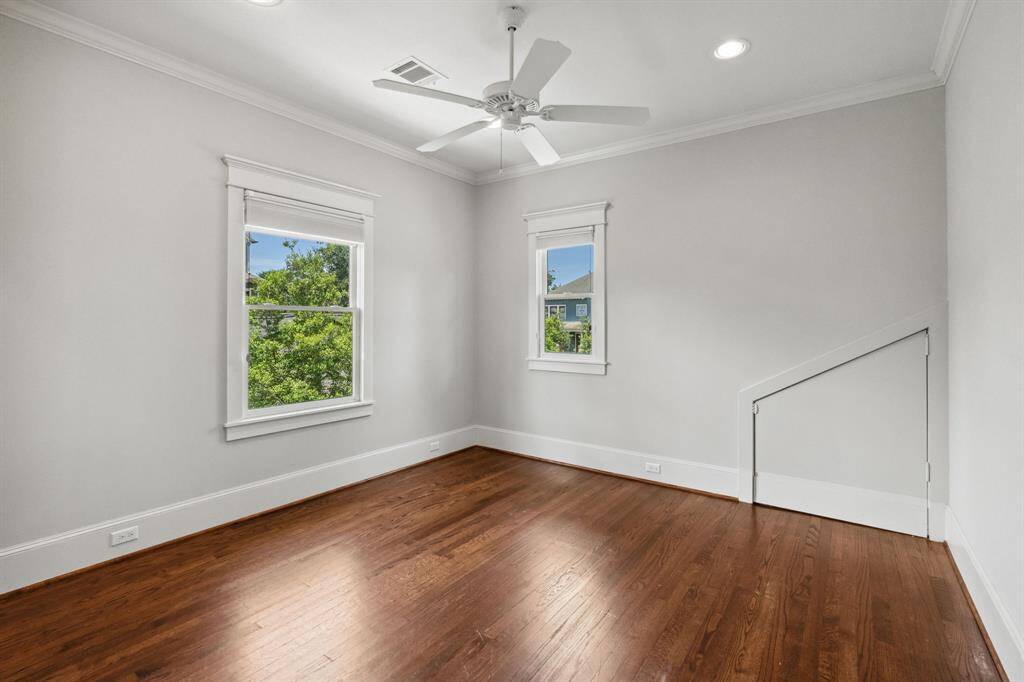 Corner bedroom with two large windows, hardwood floors, and a charming under-eave storage door.