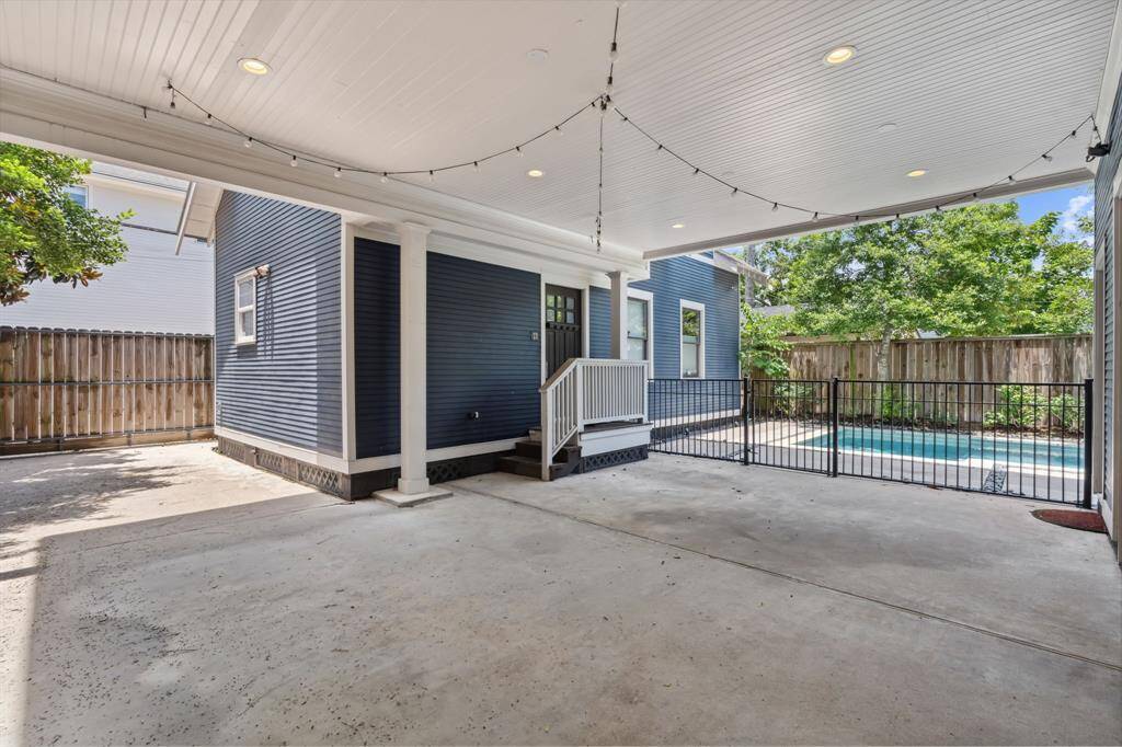 Covered carport with string lights and gated access to both the home and pool, ideal for parking or entertaining.