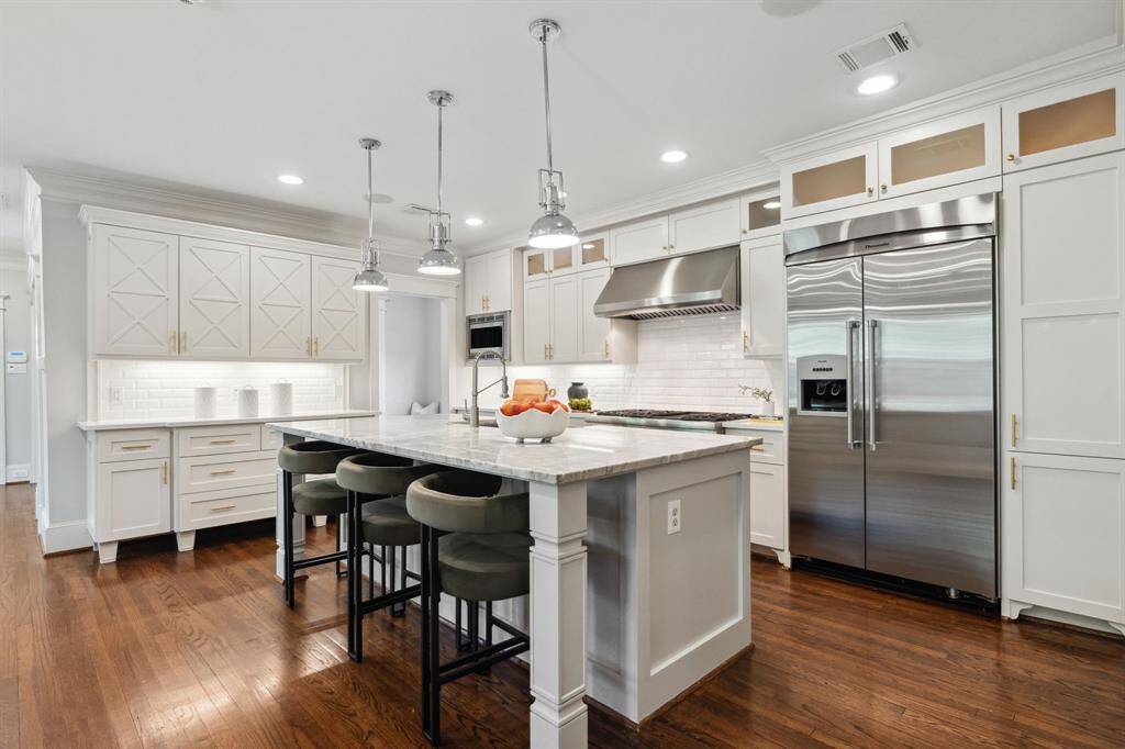 Crisp white cabinetry, marble island, and designer lighting bring the wow factor