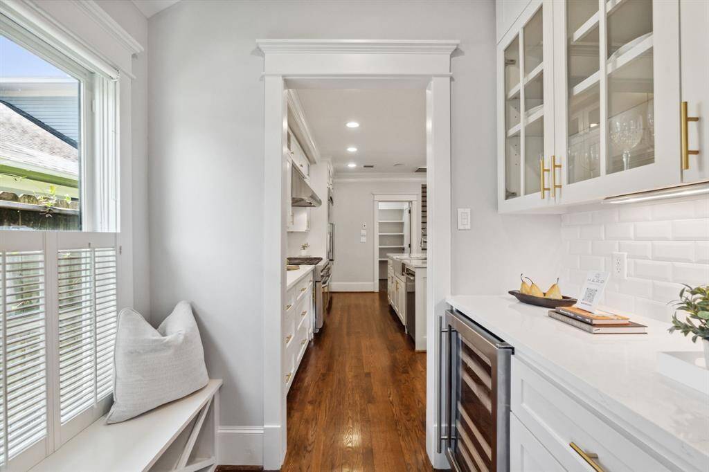 Custom butler’s pantry with wine fridge, glass-front cabinets, and charming window seat.