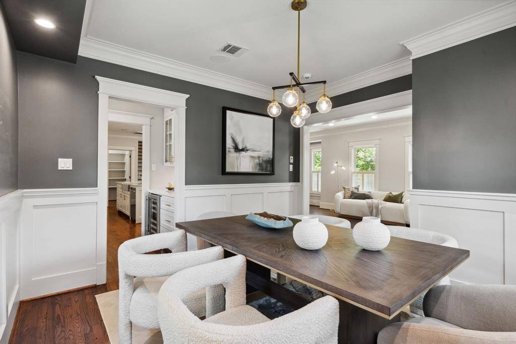 Sophisticated dining room with bold contrast walls, designer lighting, and wainscoting detail