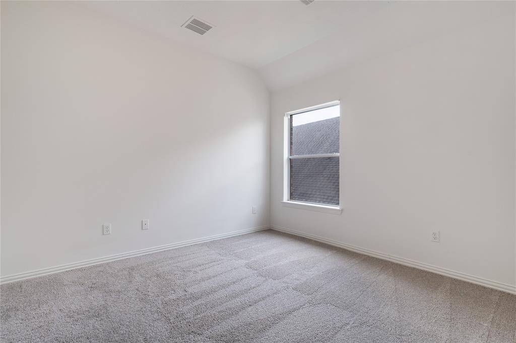 This is a bright, clean room with neutral walls and a plush carpet, featuring a single window that provides natural light.
