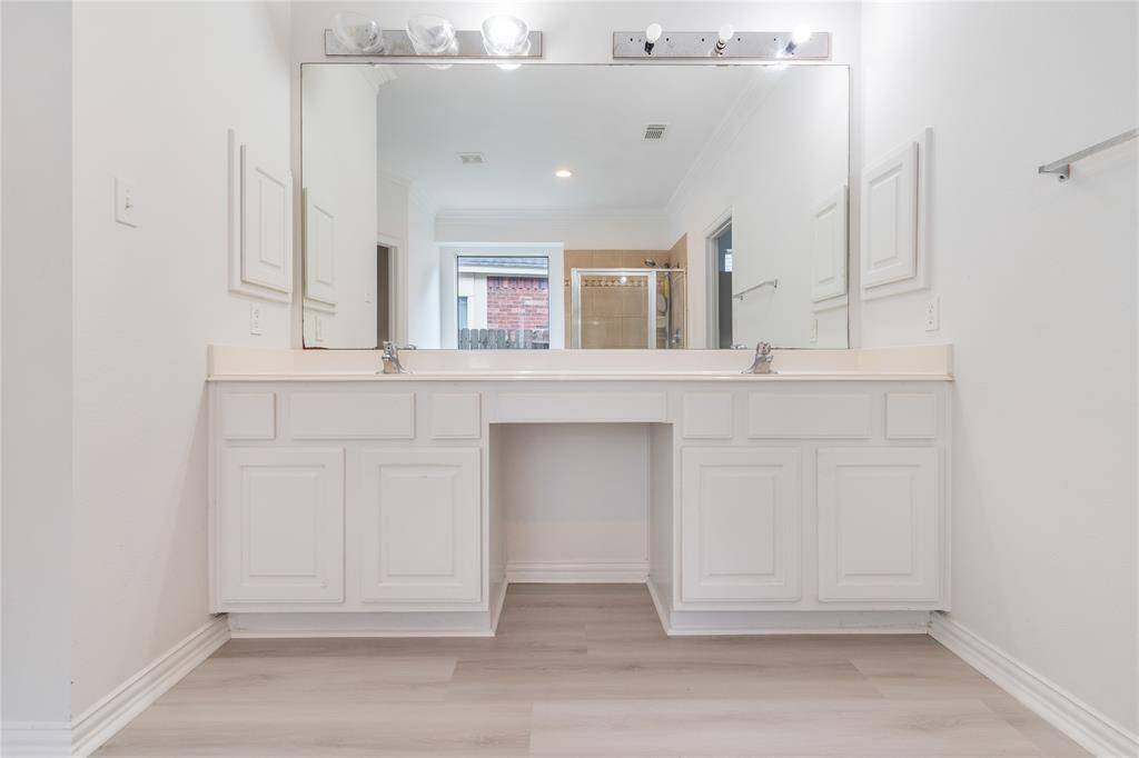 This is a clean and modern bathroom vanity area with a dual sink setup, ample cabinetry, a large mirror, and good lighting, perfect for a contemporary home.