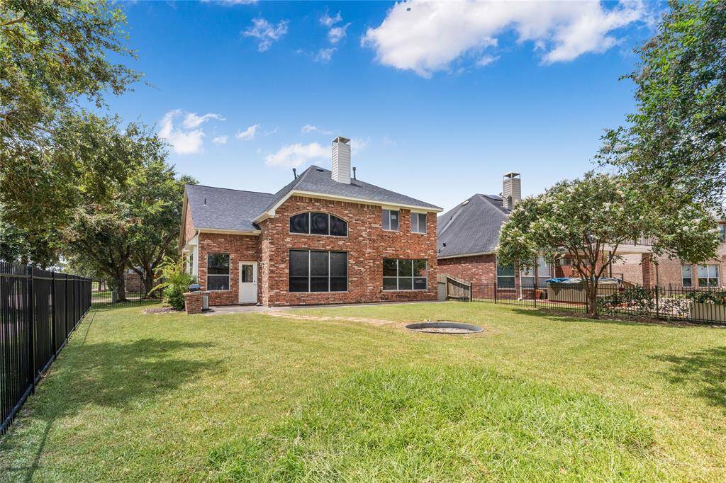 This is a two-story brick home featuring a spacious backyard with a well-maintained lawn, a privacy fence, and mature trees.